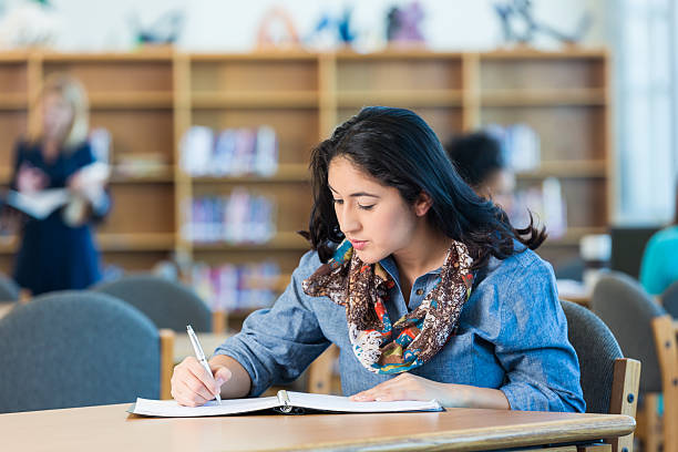istock Pretty mid adult Hispanic woman using notebook in college library 468822674