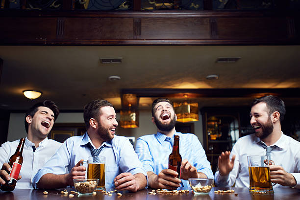 Laughing men Four businessmen sitting at pub after work stag night stock pictures, royalty-free photos & images