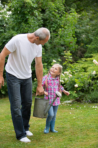 istock Father and daughter carrying watering can 468824330