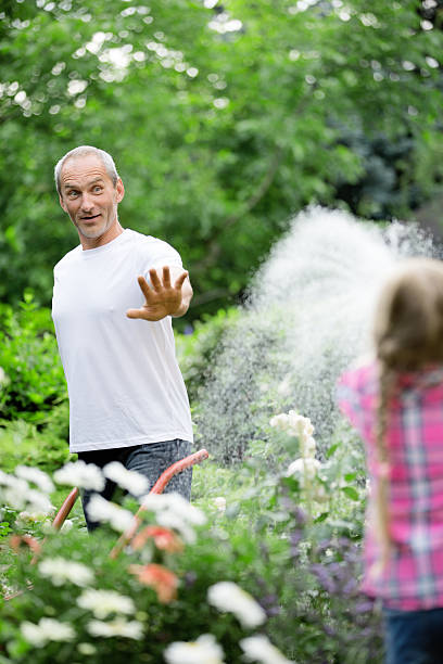 istock Father and daughter watering plants in garden 468824340