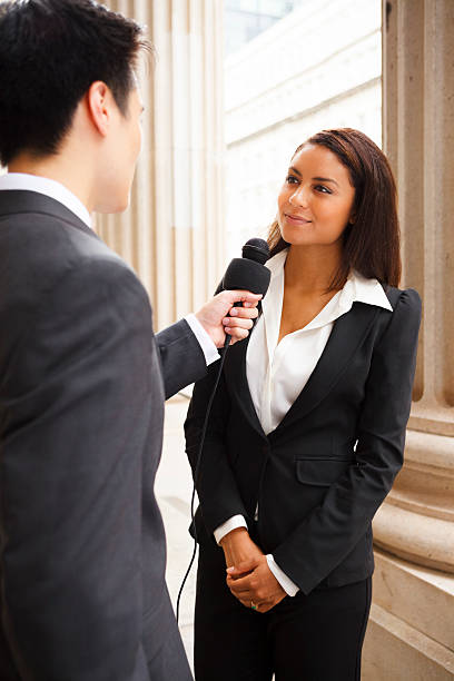 istock Well-dressed man with mic interviewing well-dressed woman 468831363