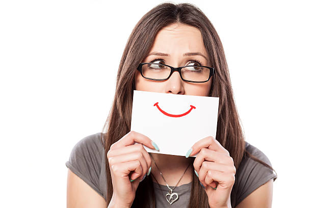 istock Sad young woman with smile painted on paper 468833062