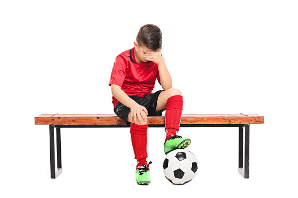 istock Sad kid in soccer uniform sitting on a bench 468833332