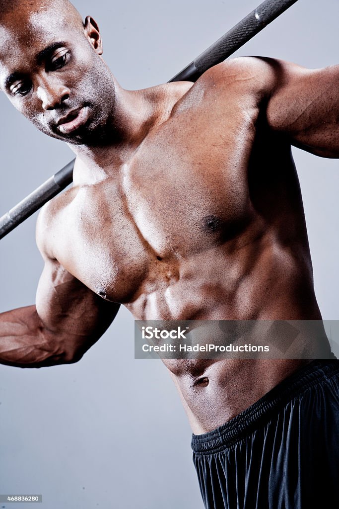 Bodybuilder posing with weight bar African American Bodybuilder posing with weight bar on grey background. 2015 Stock Photo