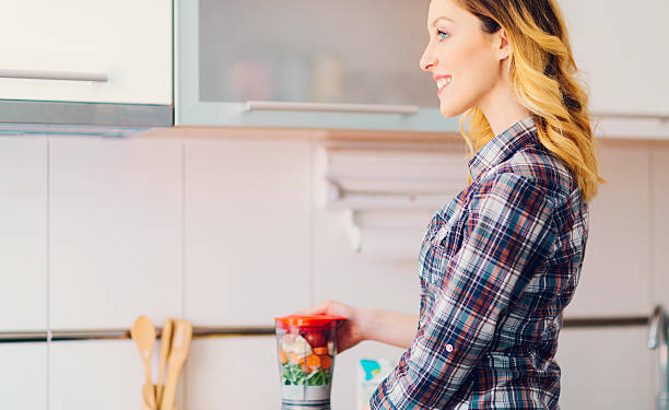 Young Smiling Woman making fresh smoothie or juice.