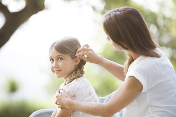 istock Mother fixing daughter's hair outdoors 468837509