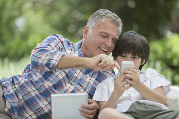 Grandfather and grandson using digital tablet and cell phone two kindle phones stock pictures, royalty-free photos & images