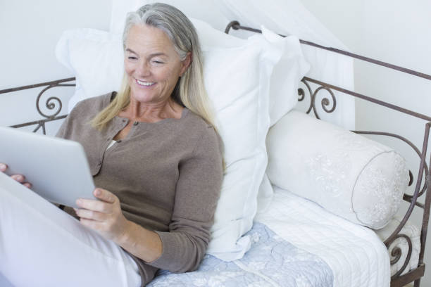 Senior woman using digital tablet on bed  chaise longue woman stock pictures, royalty-free photos & images