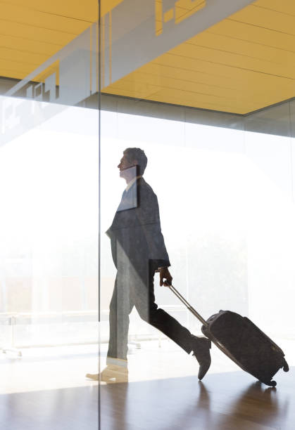 biznesmen ciągnąć walizka w airport korytarz - business travel zdjęcia i obrazy z banku zdjęć