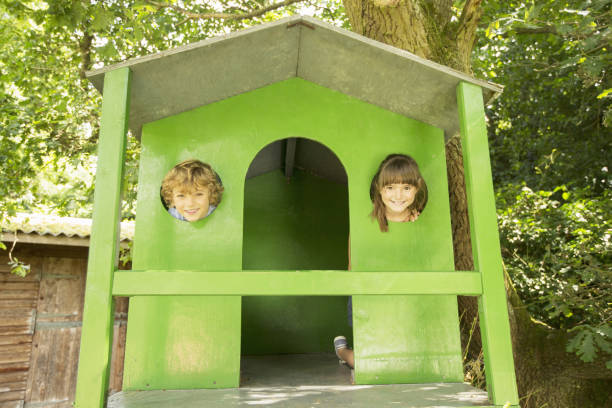 istock Children peeking through windows of treehouse 468838373