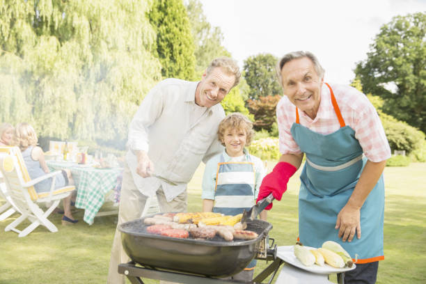 多世代男性グリルミート、トウモロコシの裏庭でのバーベキュー - barbecue grill barbecue burger hamburger ストックフォトと画像