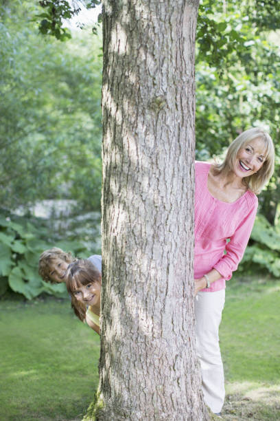 istock Grandmother and grandchildren peering behind tree 468838497