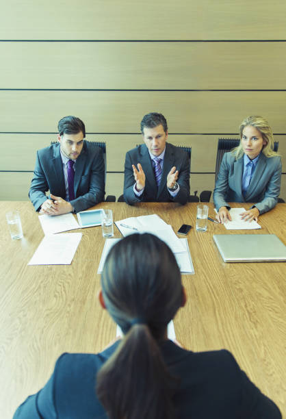 Close up shot of unrecognizable businesswoman sitting at her desk, holding a clipboard and writing notes while interviewing a candidate for a job.