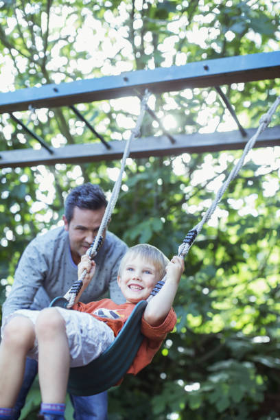 istock Father pushing son on swing outdoors 468839793