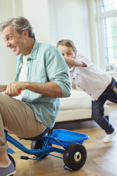istock Boy pushing father on tricycle indoors 468839807