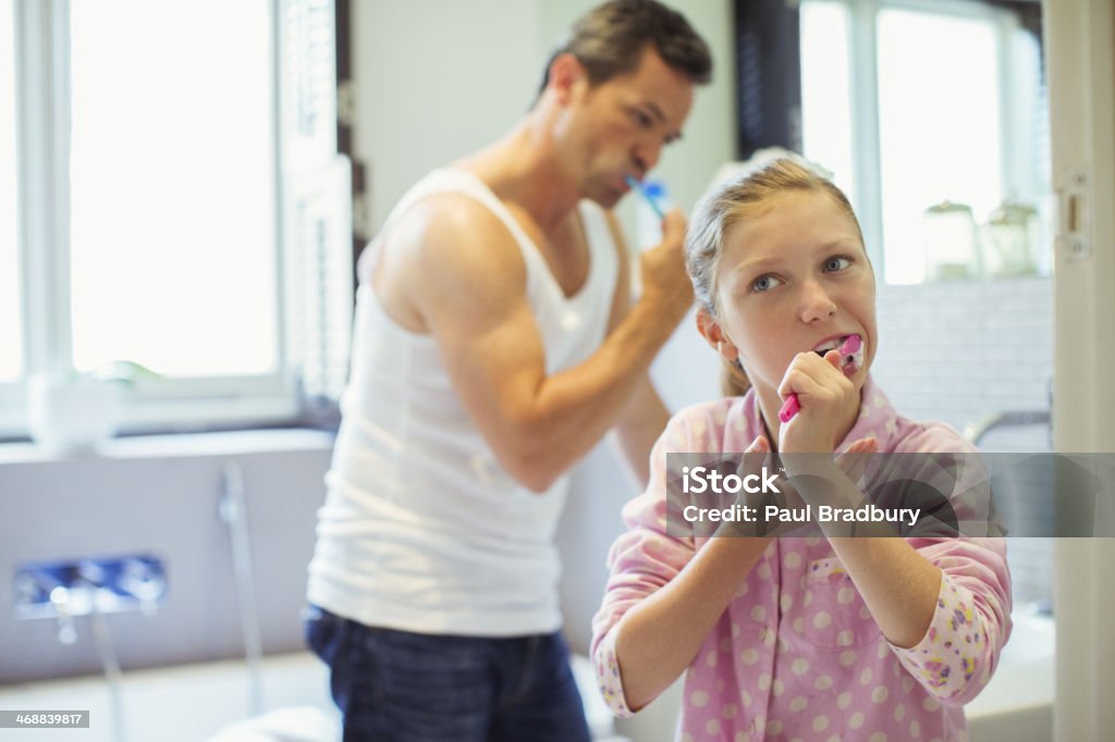 Father and daughter brushing teeth in bathroom  10-11 Years Stock Photo