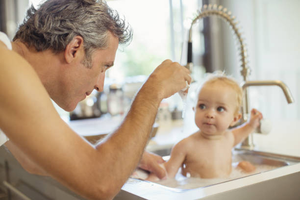 istock Father bathing baby in kitchen sink 468839917