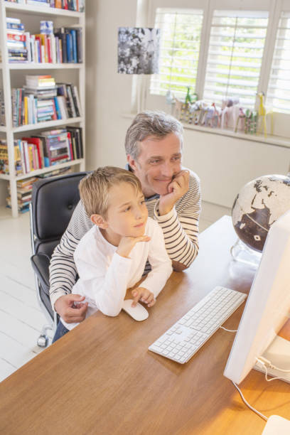 父と息子が一緒にコンピュータを使用 - kid reading ストックフォトと画像