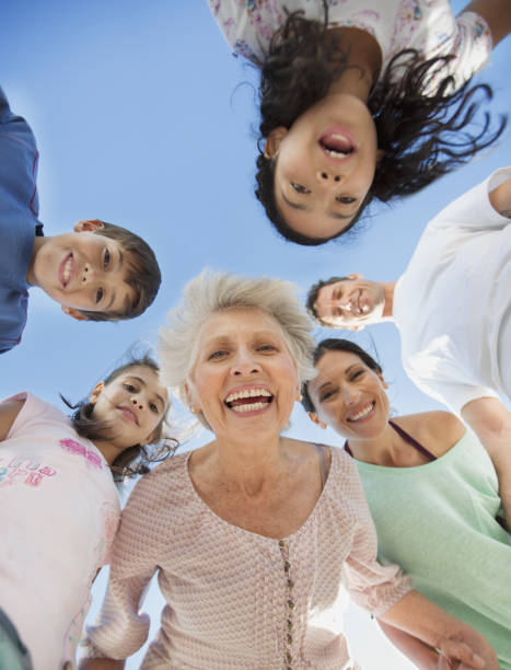 familia multi-generacional sonriendo en huddle - grandmother standing senior women senior adult fotografías e imágenes de stock