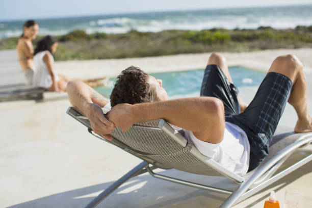 istock Man relaxing in lounge chair at poolside 468840377