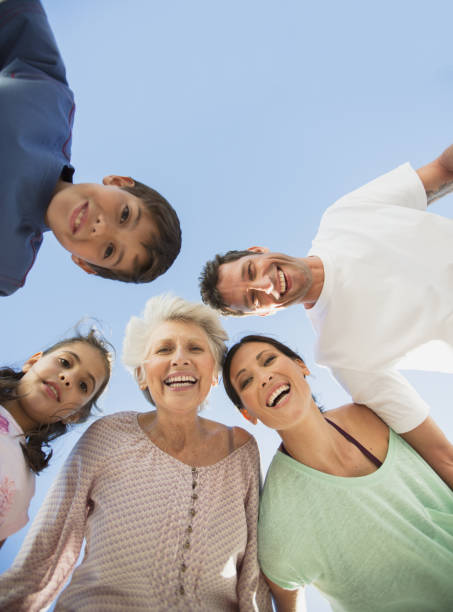 istock Multi-generation family smiling in huddle against blue sky 468840421