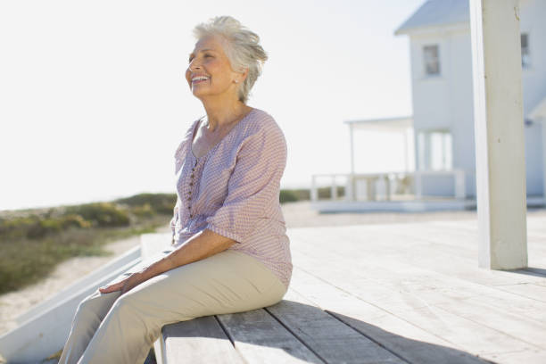 istock Senior woman sitting on deck outside beach house 468840451