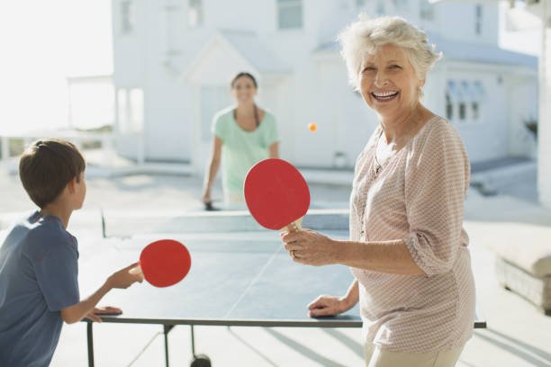 multi поколения семьи играть в настольный теннис за пределами beach house - grandmother action senior adult grandparent стоковые фото и изображения