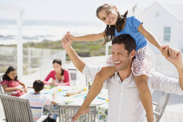 istock Father carrying daughter on shoulders on sunny patio 468840533