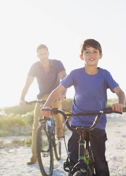 istock Father and son riding bicycles on sunny beach 468840559