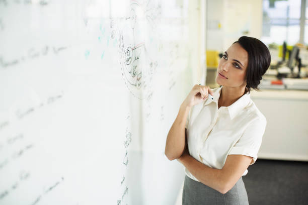 istock Businesswoman looking at whiteboard in office 468840917