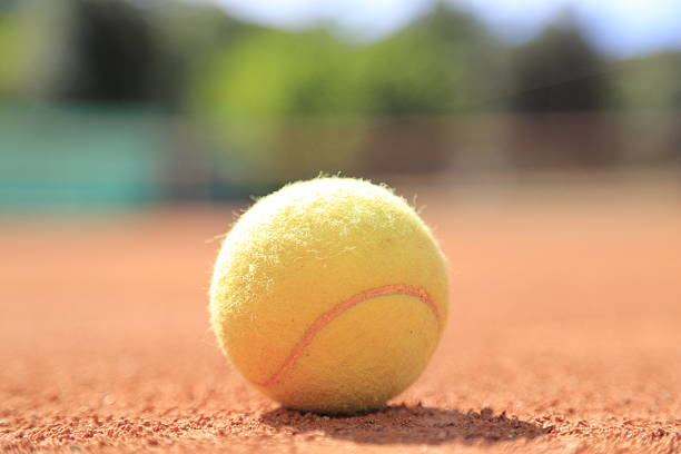 tennis ball on a sand court stock photo