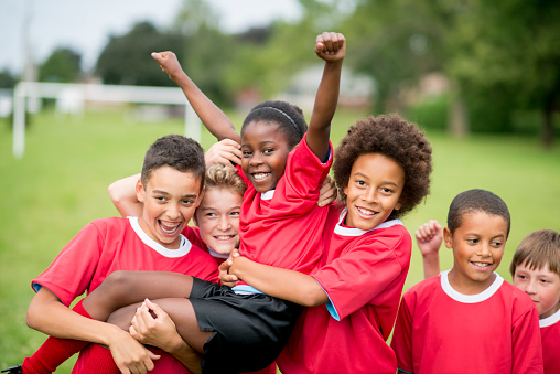 A group of children on a soccer team wearing red jerseys, celebrating their victory together.