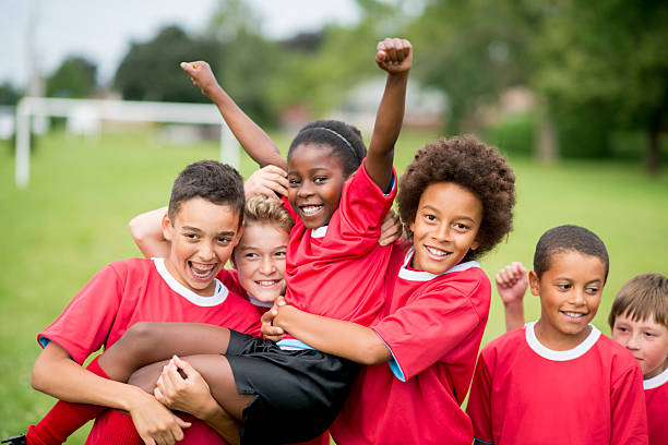 Soccer Team Victory A group of children on a soccer team wearing red jerseys, celebrating their victory together. team sport stock pictures, royalty-free photos & images