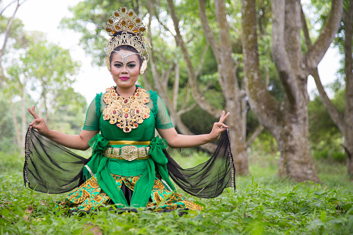 Young Sundanese dancer sitting in full make-up and costume dancing in the forest.