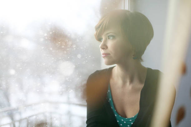 istock sad girl on the windowsill looking out the window 468857188