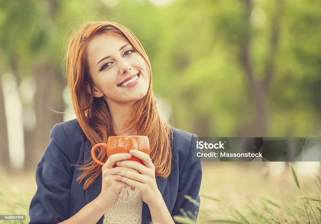 Redhead girl with orange cup at outdoor Adult Stock Photo