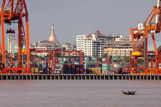 Yangon harbour Yangon, Burma - March 10, 2015: Yangon harbur seen from a ship entering the harbor. The golden famous Shwedagon Pagoda in the background. A small boat filled with passengers surrounded by sea gulls is in the foreground. Cargo containers and cranes  can be seen at the docks. yangon photos stock pictures, royalty-free photos & images