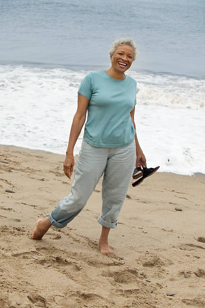 istock Smiling Woman Walking Barefoot on Beach 468860009