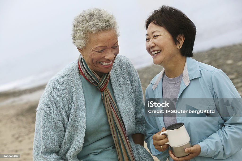 Two Friends Talking over Coffee on the Beach Mature Women Stock Photo