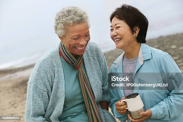 Two Friends Talking Over Coffee On The Beach Stock Photo - Download Image Now - Mature Women, Friendship, Discussion