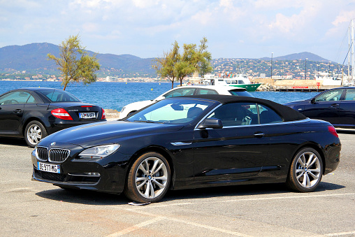 Saint-Tropez, France - August 3, 2014: Black convertible sports car BMW F12 6-series parked at the city street.