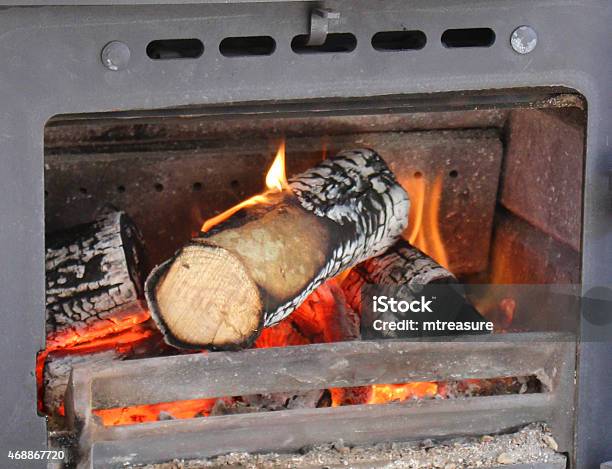 Image Of Flames Fire Inside Castiron Woodburning Stove Burning Logs Stock Photo - Download Image Now