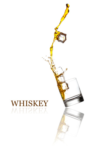Glass with splashing whisky drink. Isolated on a white background