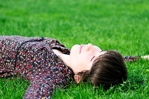 istock Young woman lying on green grass 468874203