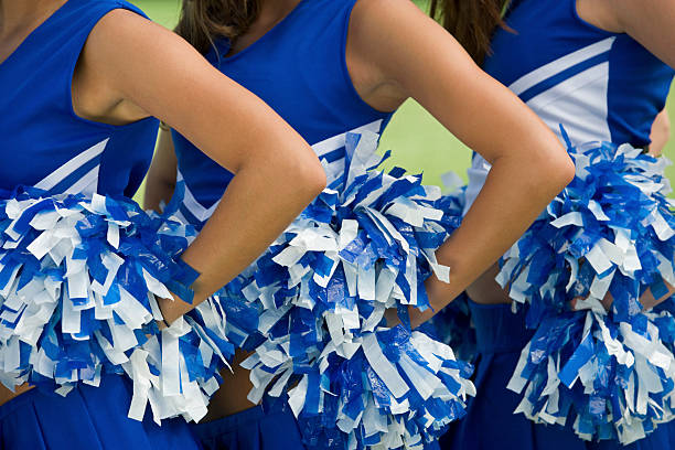 istock Three cheerleaders in blue and white uniform and pom-poms 468874803