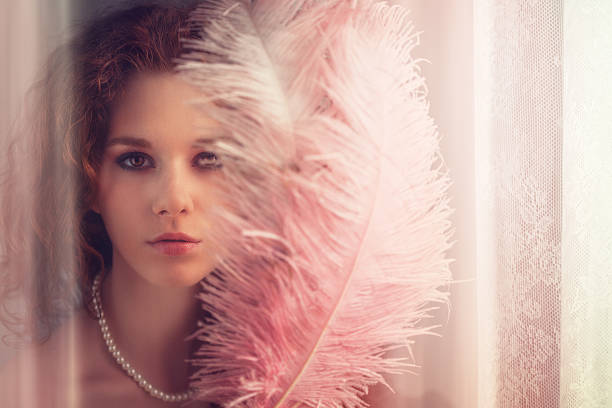 young girl with feather fan by the window