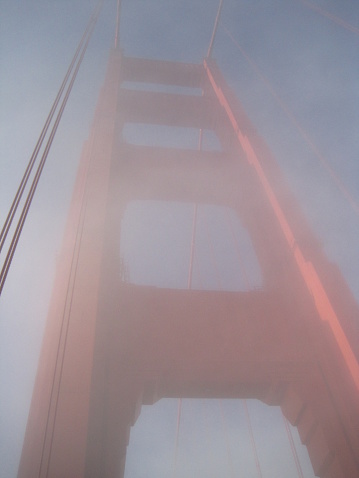 the famous red bridge emerging from behind the clouds, gloomy photo of the golden gate bridge