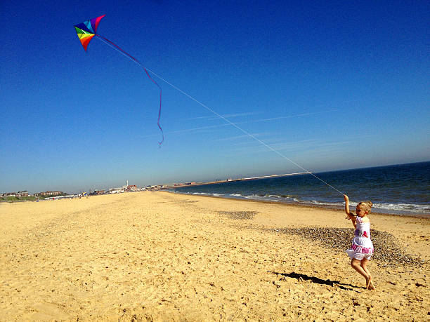 istock Little Girl Flying Kite on Beach 468880205