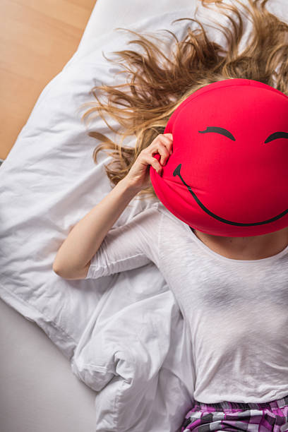 istock Girl with a smiley shaped pillow on her face 468880730