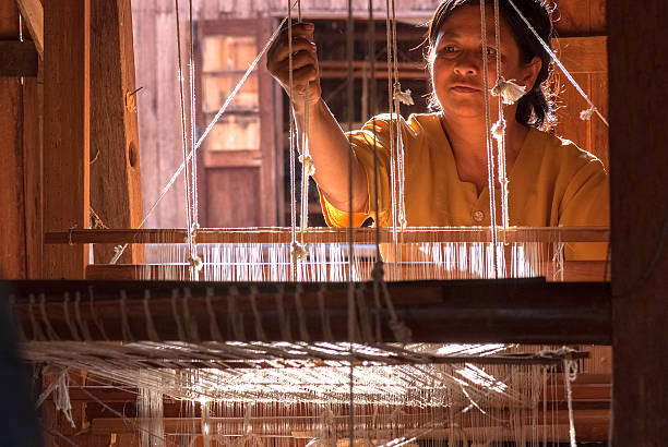 Long-neck woman from Padaung (Karen) tribe weaving on a loom, Mae Hong Son Province in Northern Thailand.